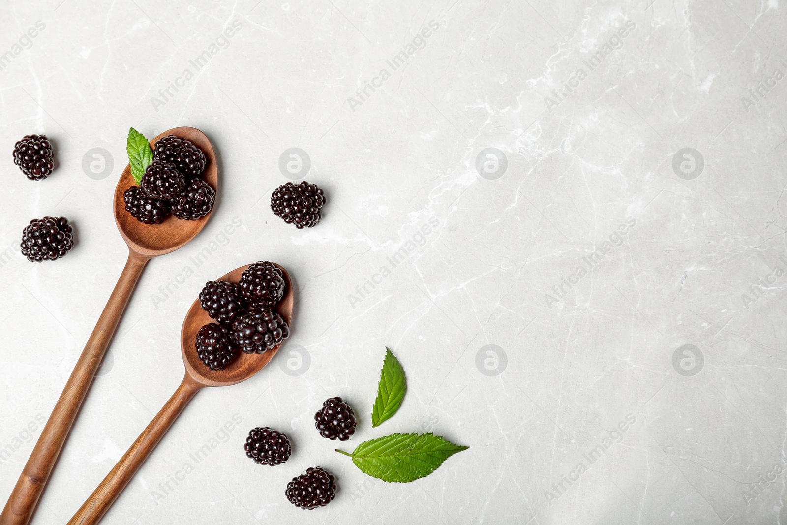 Photo of Flat lay composition with spoons of fresh blackberry and space for text on gray background