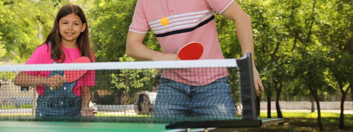 Happy man with his daughter playing ping pong in park. Banner design