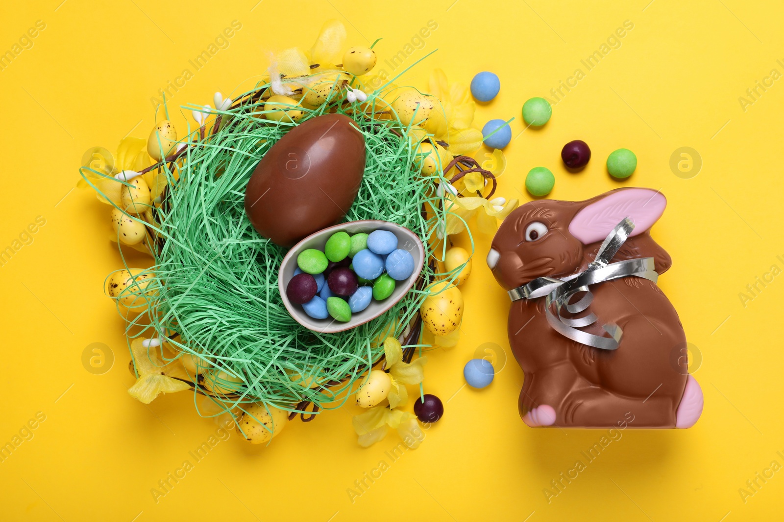 Photo of Flat lay composition with chocolate Easter bunny, eggs and candies on yellow background