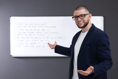 English teacher near whiteboard with task at lesson