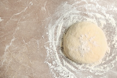 Fresh raw dough with flour on table, top view