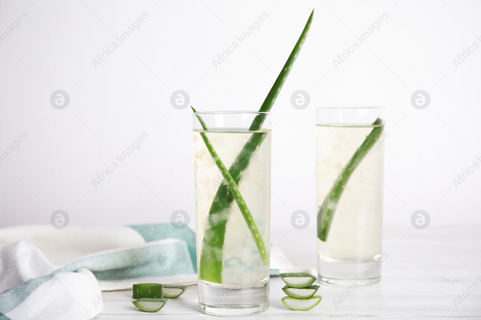 Photo of Fresh aloe drink with leaves in glasses on white wooden table