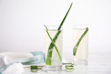 Photo of Fresh aloe drink with leaves in glasses on white wooden table