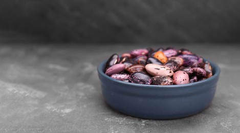 Photo of Bowl with dry kidney beans on grey table, closeup