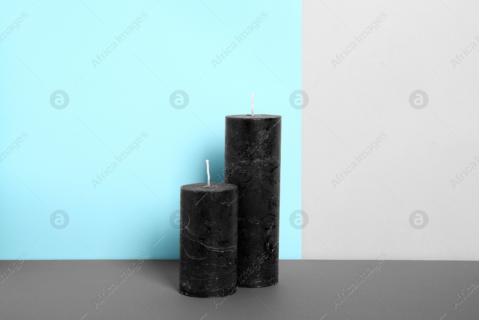 Photo of Decorative wax candles on table against color background