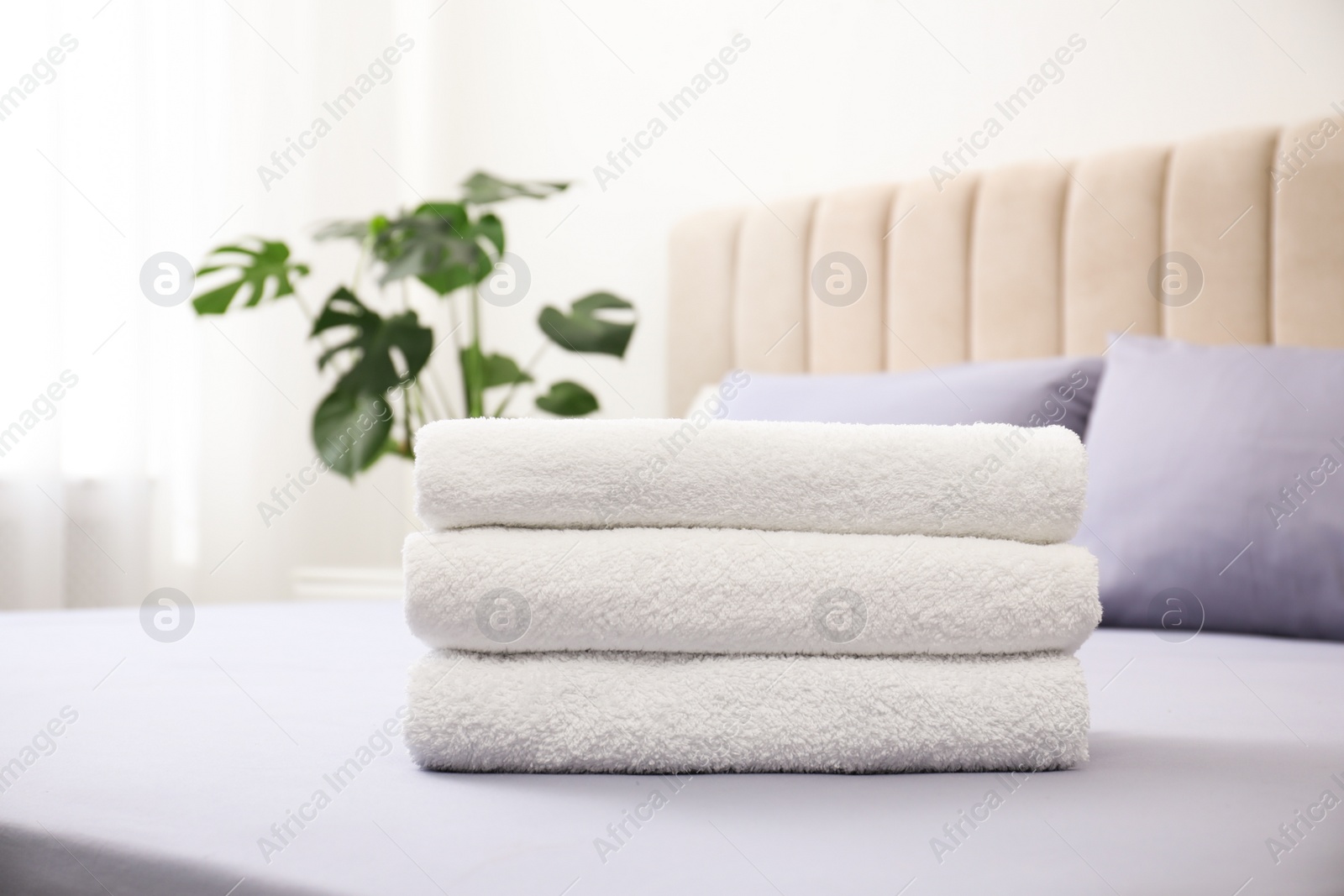 Photo of Stack of clean towels on bed indoors