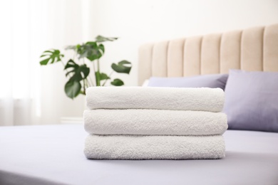 Stack of clean towels on bed indoors