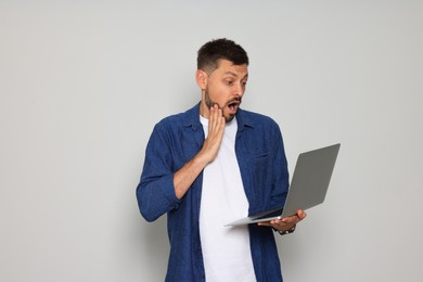 Photo of Emotional man with laptop on light grey background