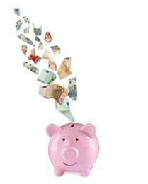 Image of Euro banknotes falling into pink piggy bank on white background