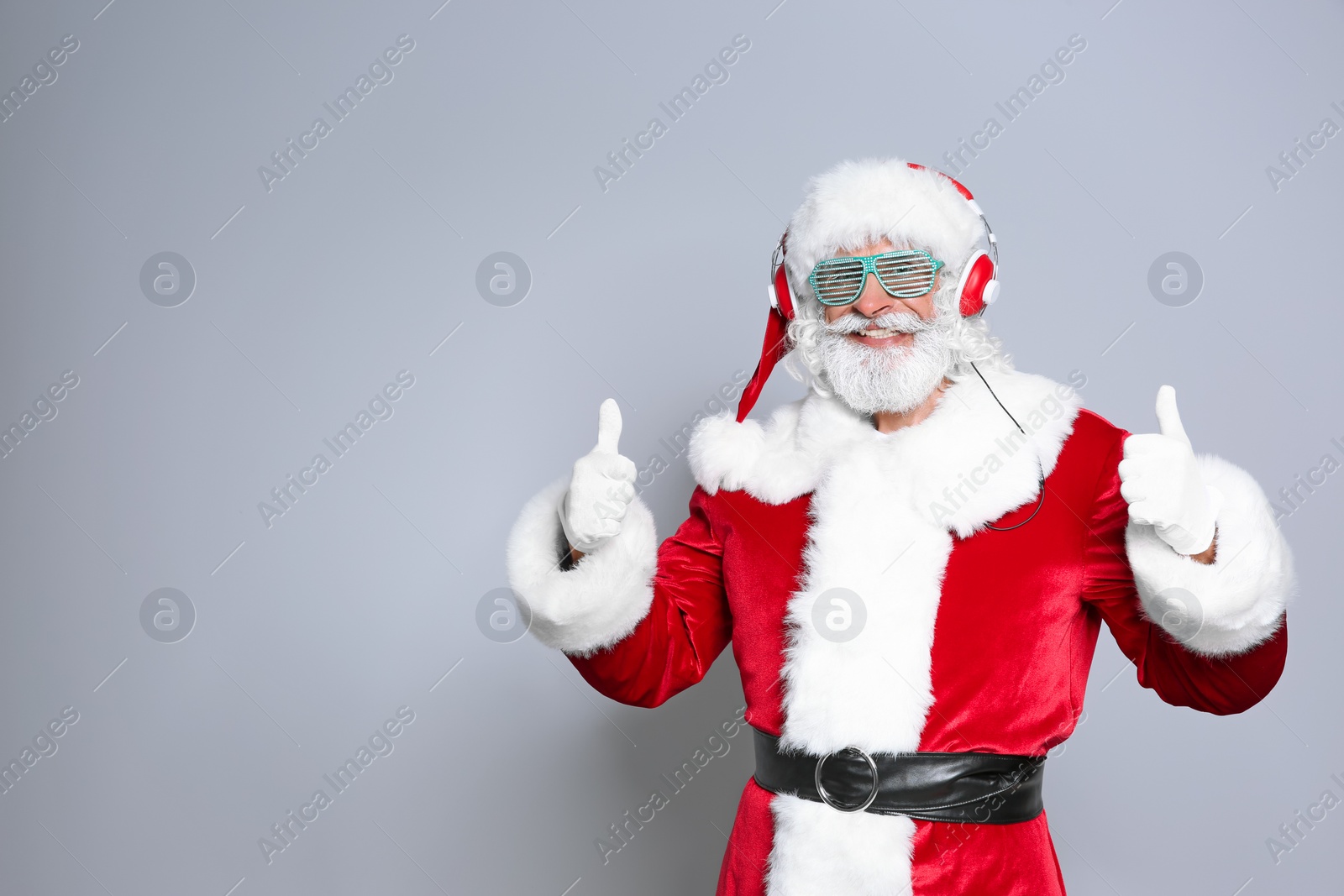 Photo of Santa Claus listening to Christmas music on color background