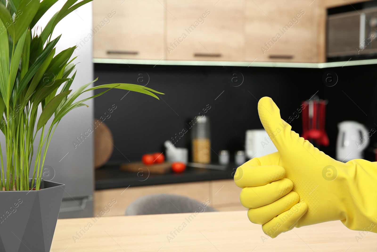 Image of Keep your home virus-free. Woman showing thumb up in clean kitchen