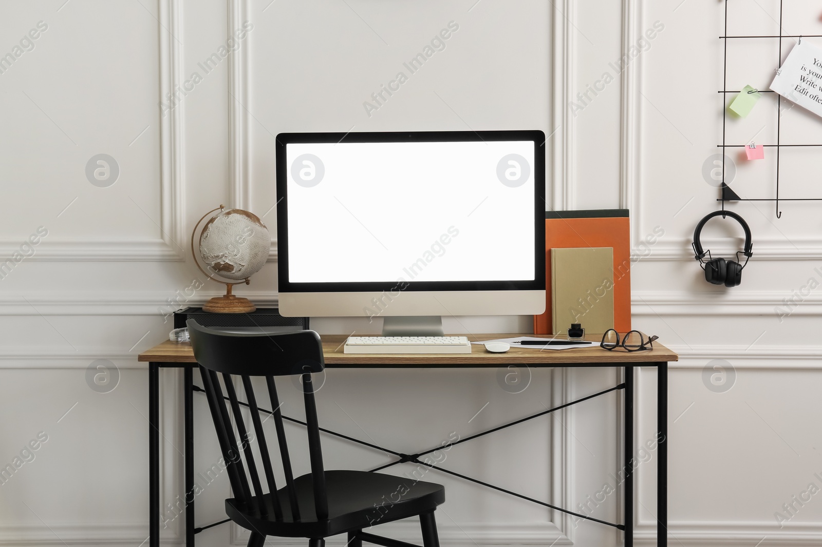 Photo of Stylish workspace with computer and stationery on wooden desk near white wall indoors