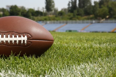 Photo of American football ball on green field grass in stadium