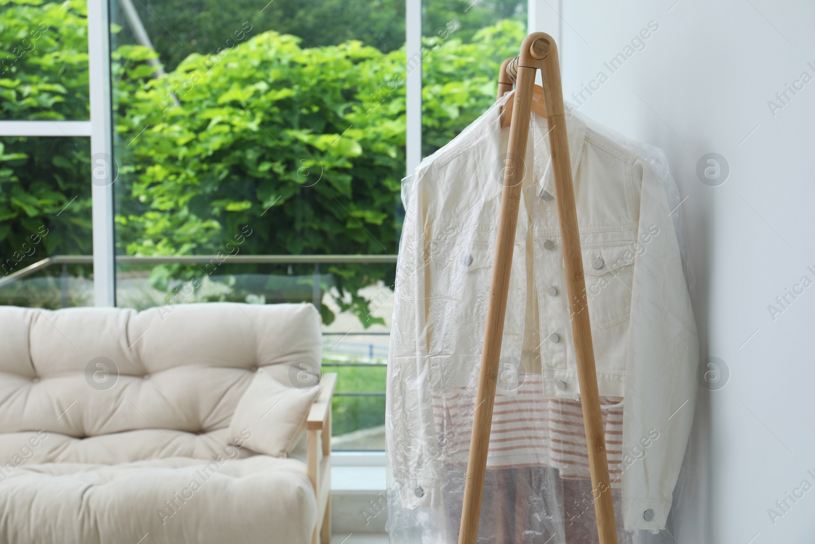 Photo of Rack with clothes in plastic bags indoors