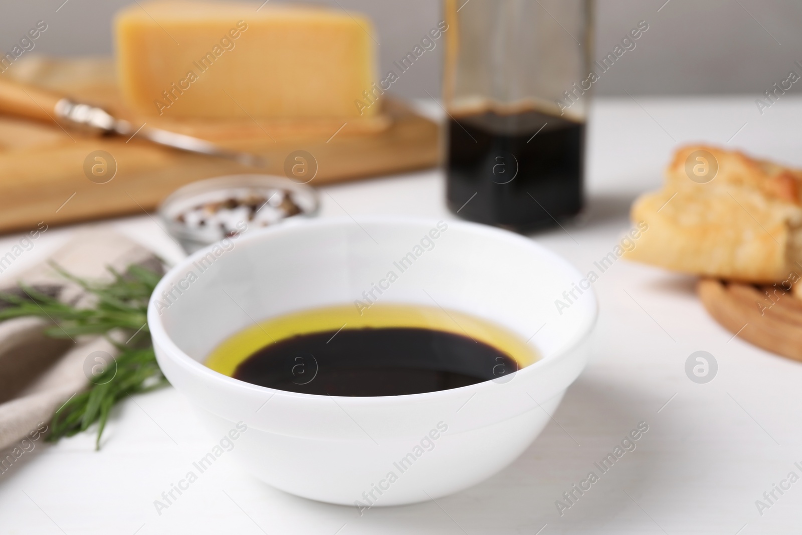 Photo of Bowl of balsamic vinegar with oil on white table, closeup