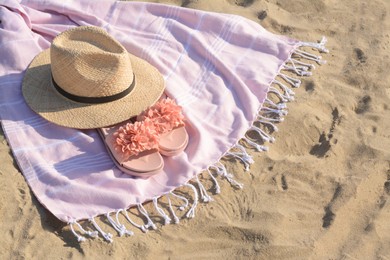Photo of Blanket with stylish slippers and straw hat on sandy beach. Space for text