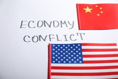 Photo of USA and China flags near words ECONOMY CONFLICT on white background