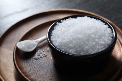 Photo of Organic white salt in bowl and spoon on table, closeup