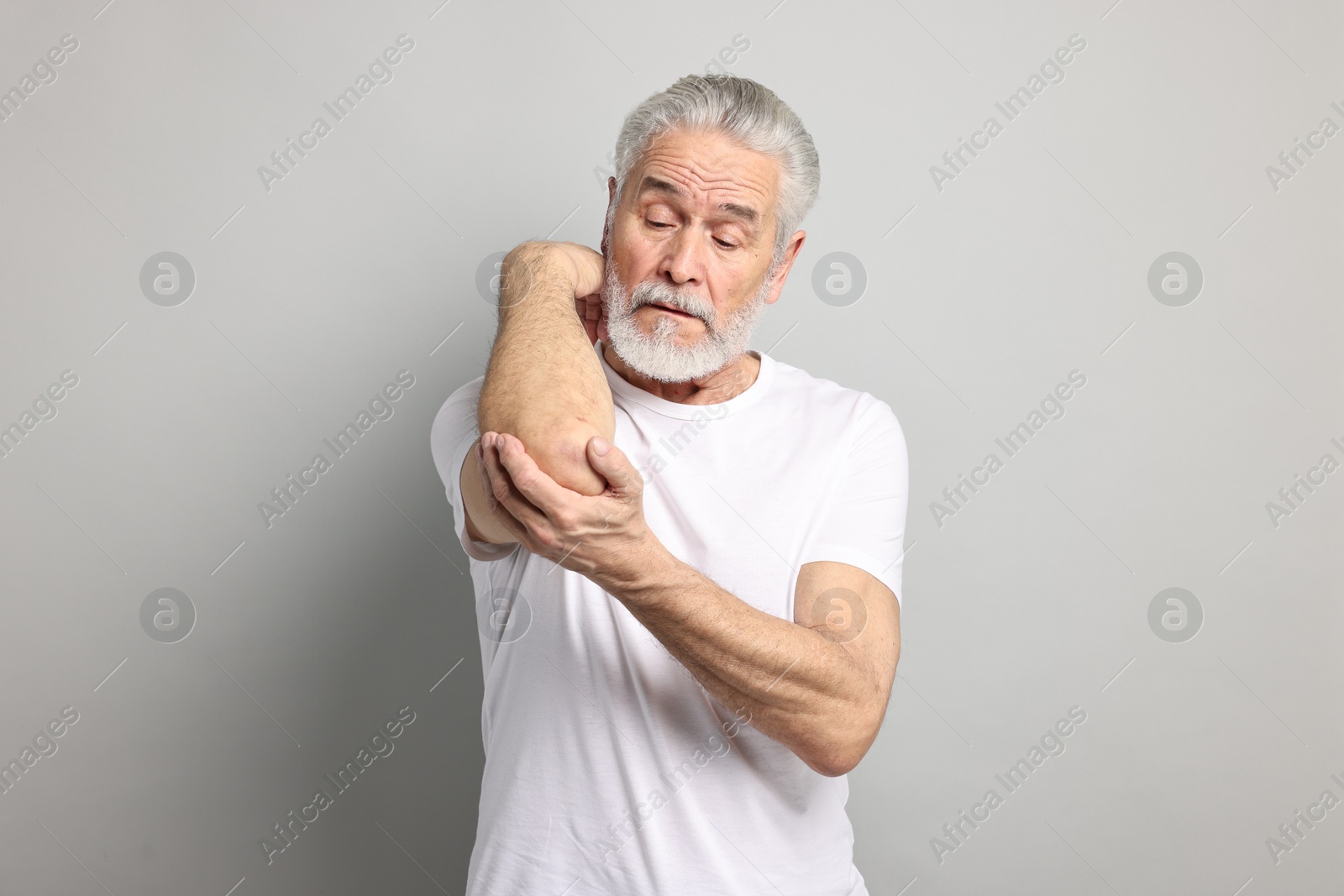 Photo of Arthritis symptoms. Man suffering from pain in elbow on gray background
