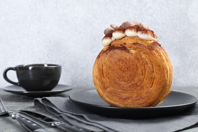 Round croissant with chocolate chips and cream served on grey table. Tasty puff pastry