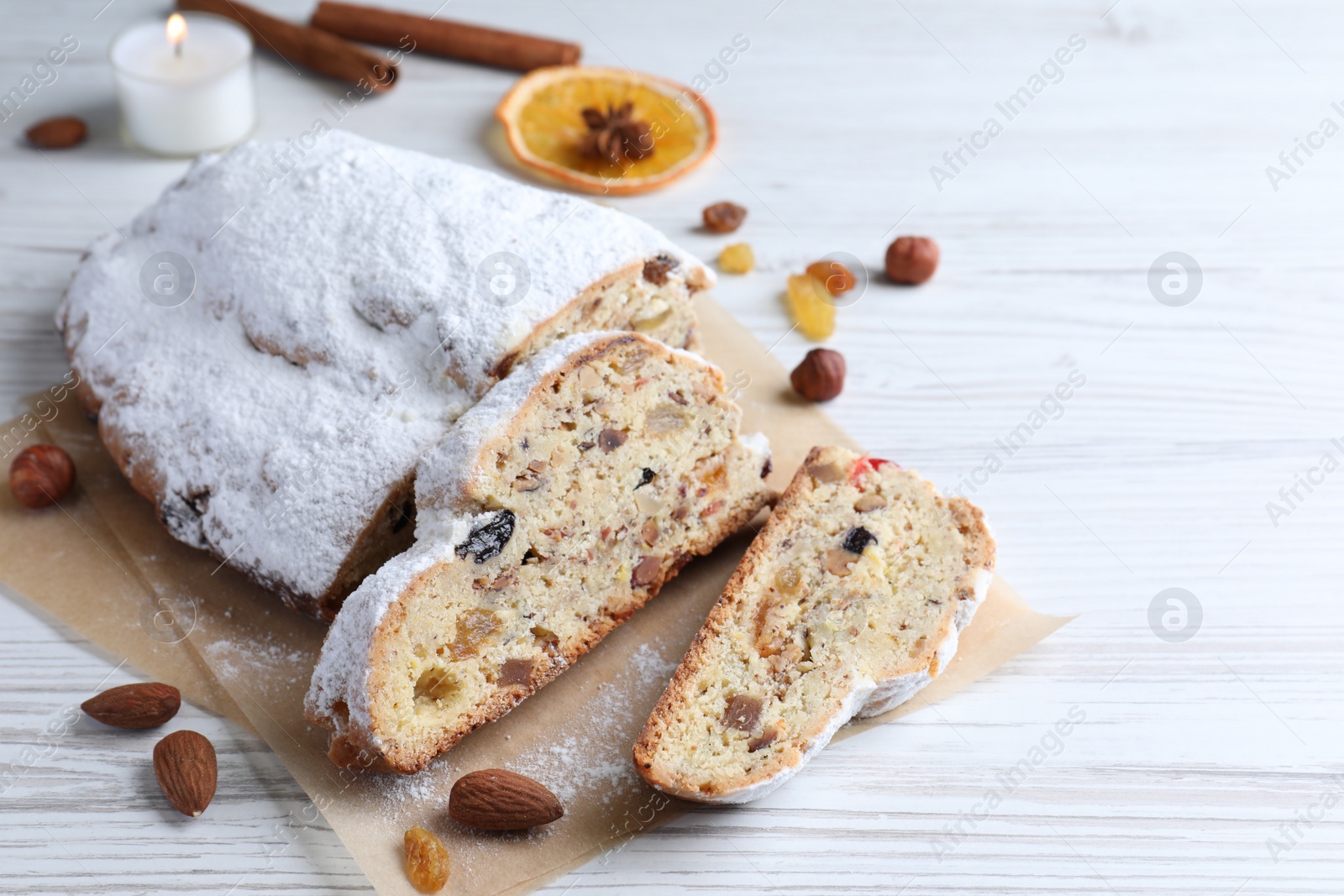 Photo of Traditional Christmas Stollen with icing sugar on white wooden table