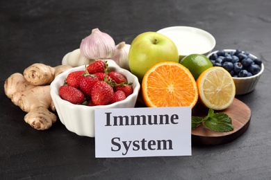 Photo of Card with phrase Immune System and fresh products on dark grey background