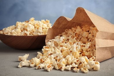 Paper bag and bowl with tasty popcorn on table