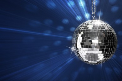 Image of Shiny bright disco ball on blue background, space for text