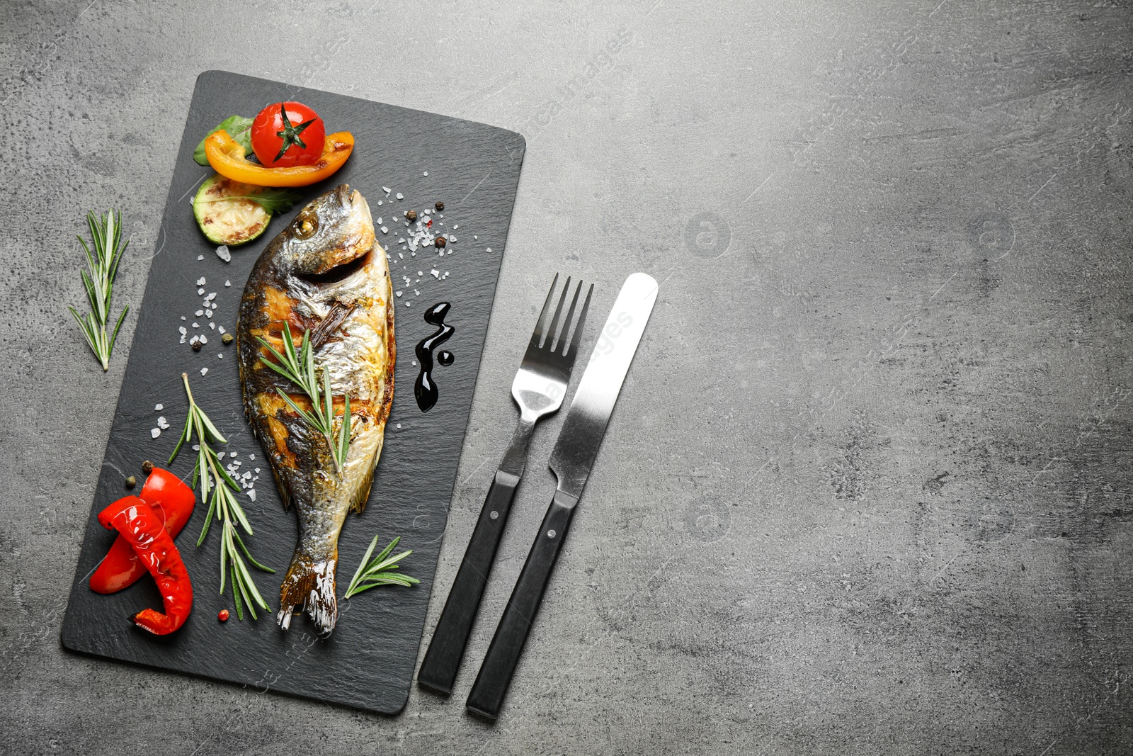 Photo of Delicious roasted fish and vegetables on grey table, flat lay. Space for text