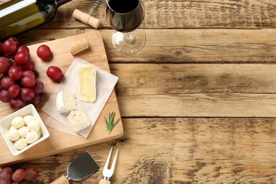 Flat lay composition with red wine and snacks on wooden table, space for text