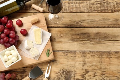 Photo of Flat lay composition with red wine and snacks on wooden table, space for text