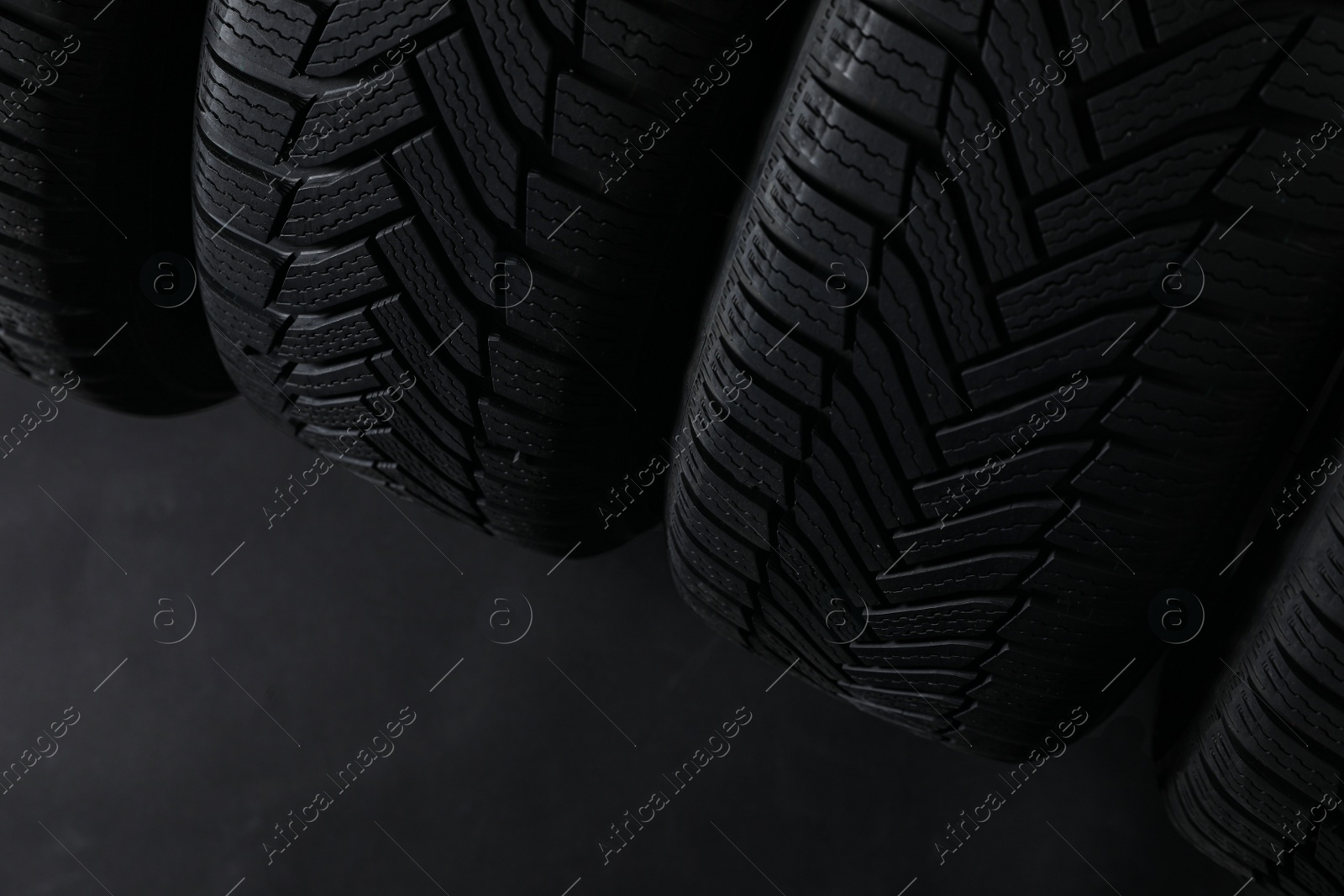 Photo of Winter tires on dark background, closeup. Space for text