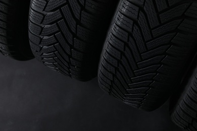 Winter tires on dark background, closeup. Space for text