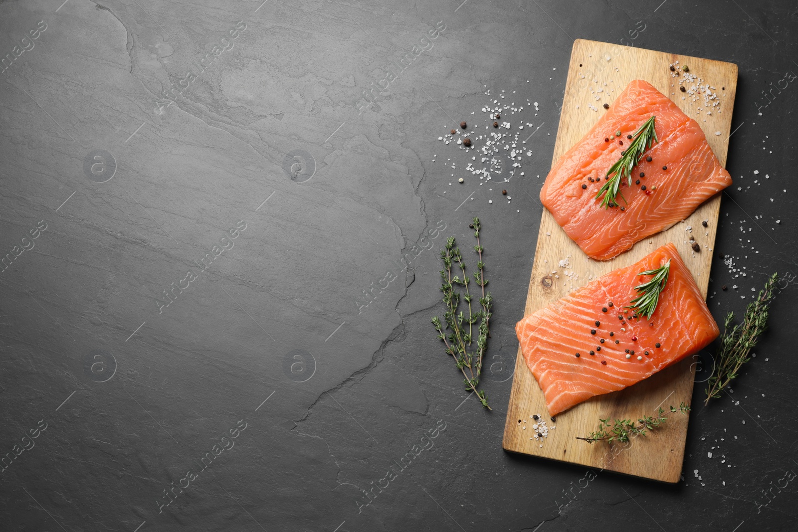 Photo of Fresh raw salmon and spices on black table, flat lay. Space for text