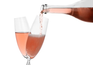 Photo of Pouring rose champagne from bottle into glass on white background