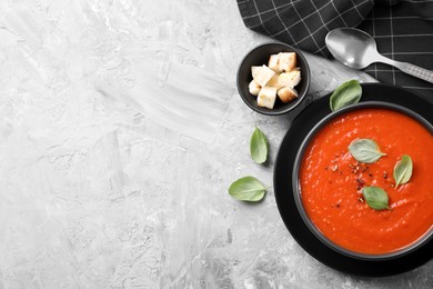 Photo of Delicious tomato cream soup served on grey textured table, flat lay. Space for text