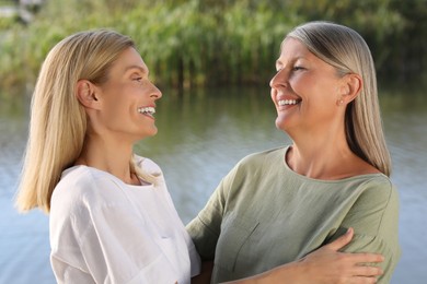 Family portrait of happy mother and daughter spending time together near pond