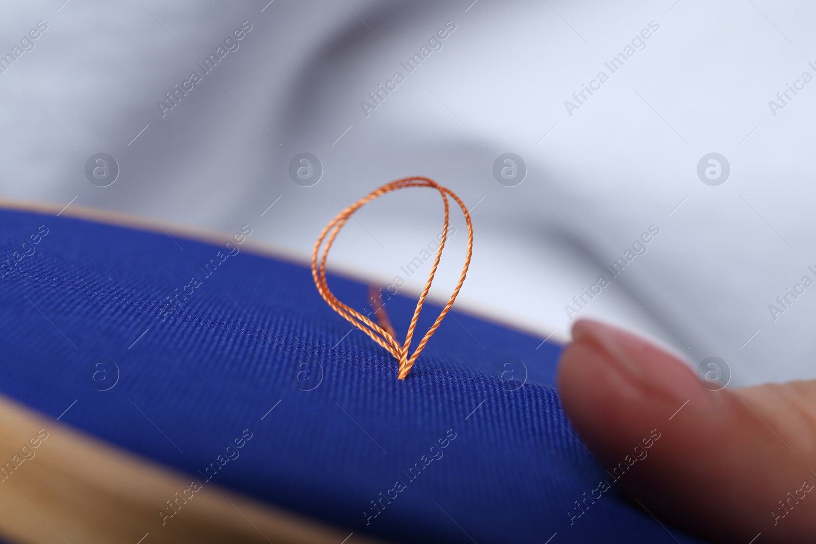 Photo of Woman with sewing thread embroidering on cloth, closeup