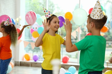 Photo of Happy children playing at birthday party in decorated room