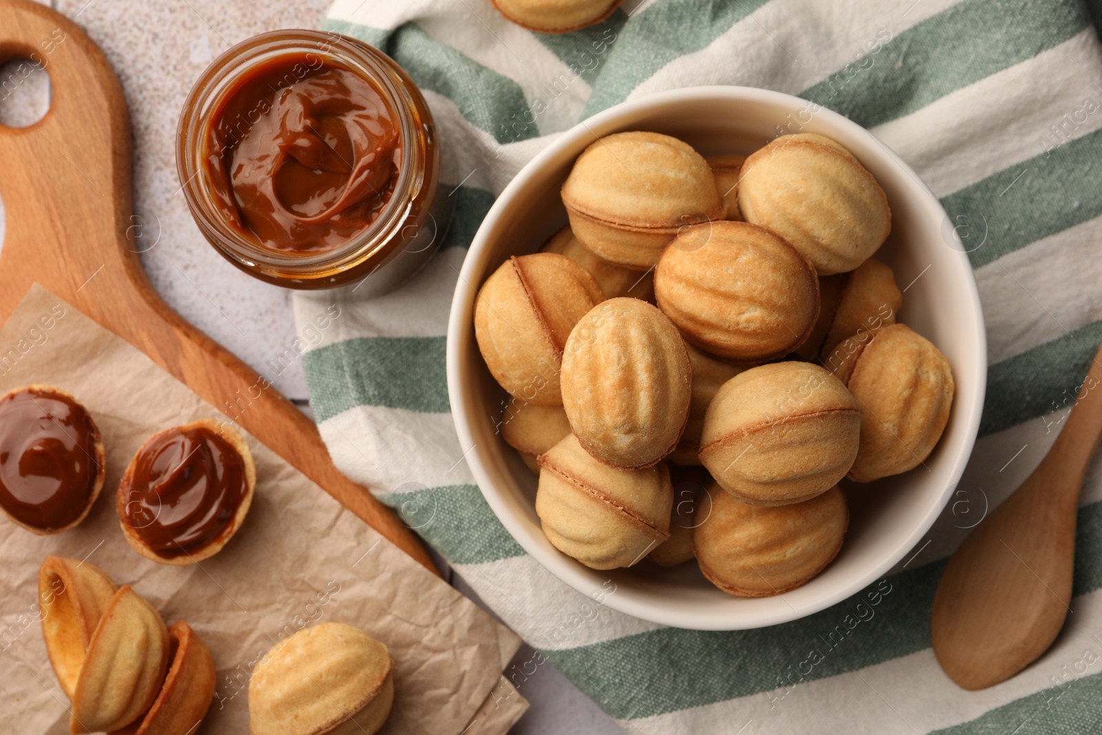 Photo of Delicious nut shaped cookies with boiled condensed milk on table, flat lay