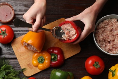 Photo of Woman making stuffed peppers with ground meat at wooden table, top view