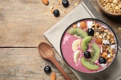 Photo of Delicious acai smoothie with granola and fruits served on wooden table, flat lay
