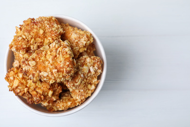 Photo of Bucket with yummy nuggets on white wooden table, top view. Space for text