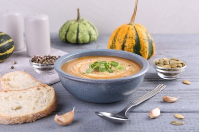 Photo of Tasty pumpkin soup served on grey wooden table