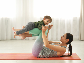 Photo of Young woman doing exercise with her son indoors. Home fitness