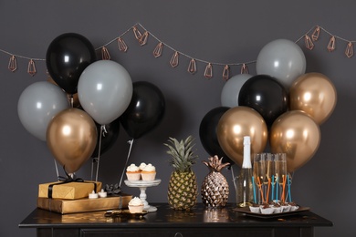Photo of Party treats and items on table in room decorated with balloons