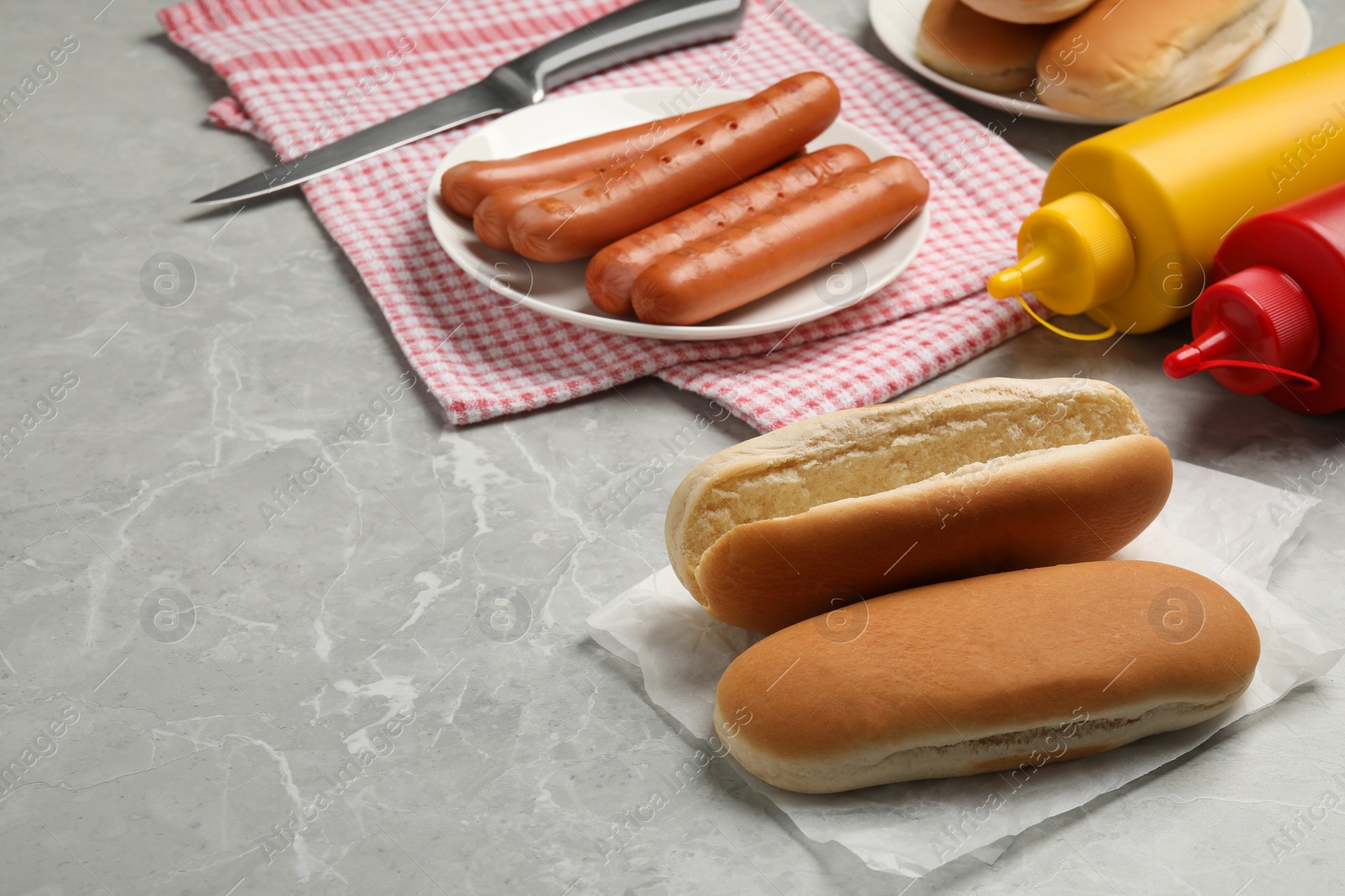 Different tasty ingredients for hot dog on light grey marble table, space for text Photo of Different tasty ingredients for hot dog on light grey marble table, space for text