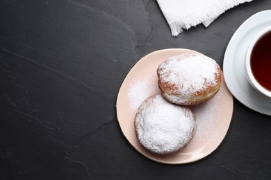 Photo of Delicious sweet buns and cup of tea on dark gray table, flat lay. Space for text