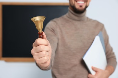 Photo of Teacher with school bell near black chalkboard closeup. Space for text