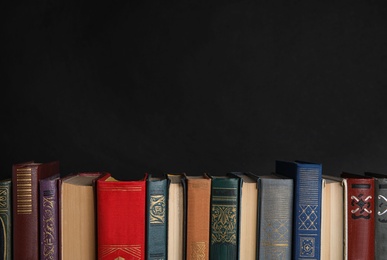 Photo of Stack of hardcover books on black background. Space for text